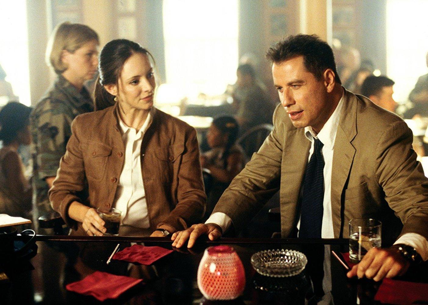 John Travolta and Madeline Stowe at a bar.