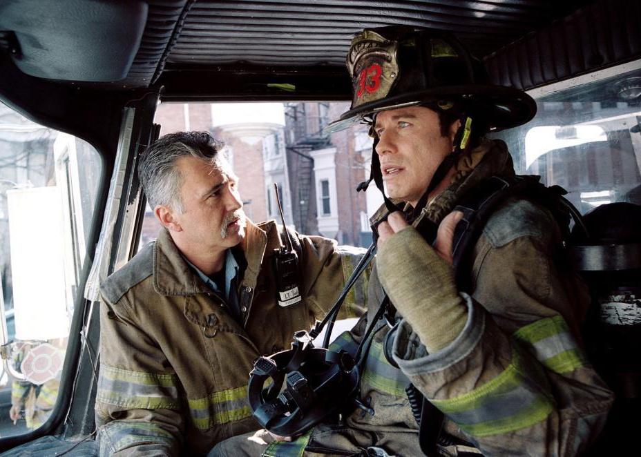 John Travolta and an older man dressed as firefighters in an engine.