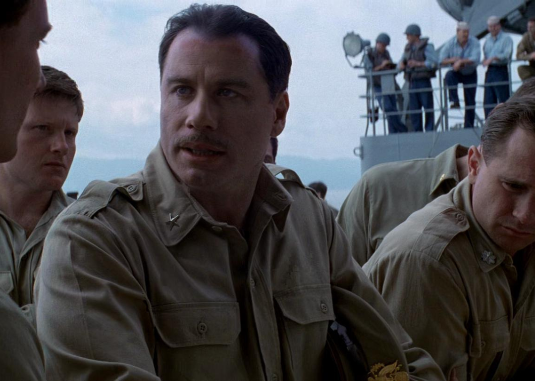 John Travolta in military uniform on a ship talking to other soldiers.