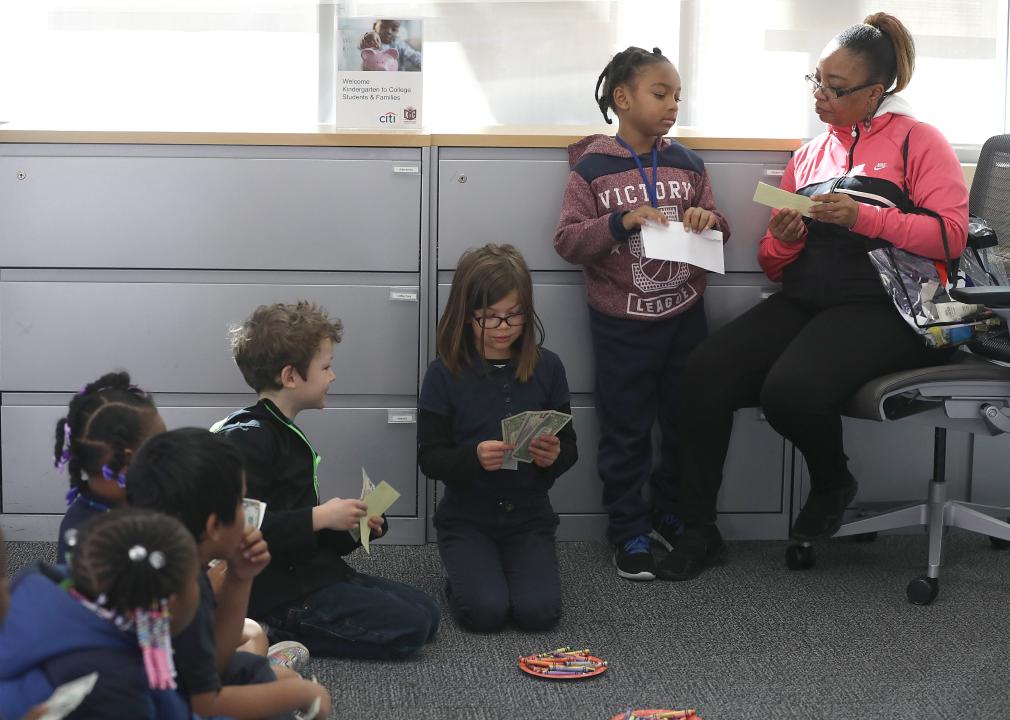 Kids sit and learn about money at a bank.