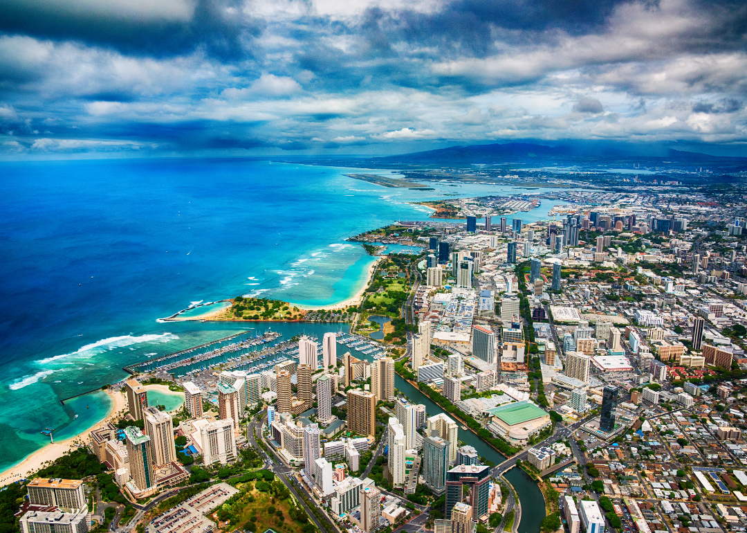 An aerial view of downtown Honolulu next to turquoise water.