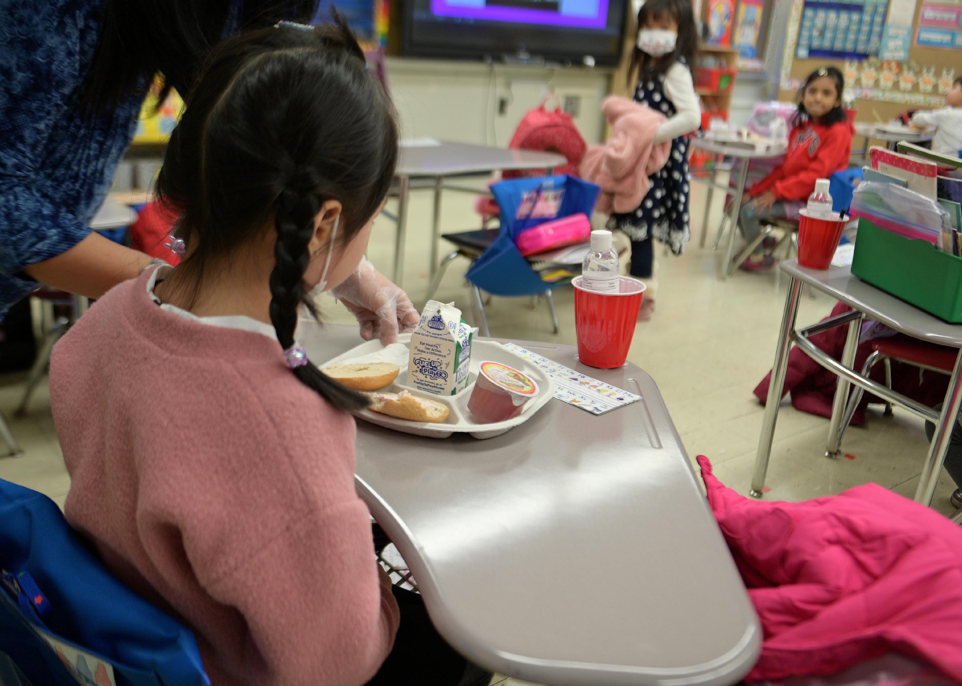 A kindergarten girl being served a lunch tray