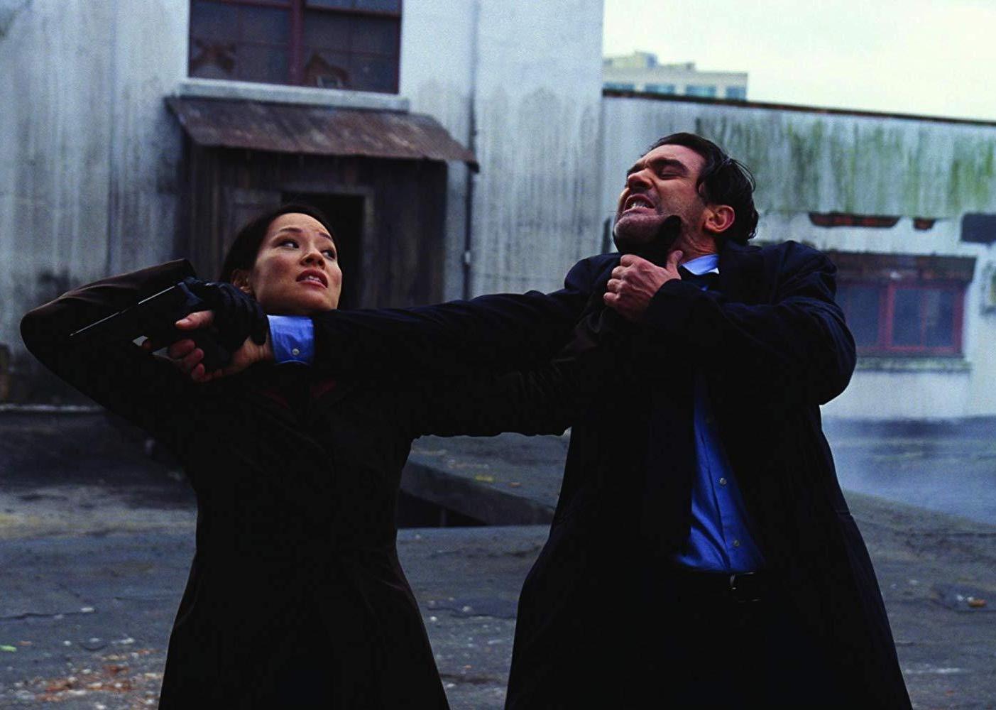 A man and woman struggle outside an industrial facility