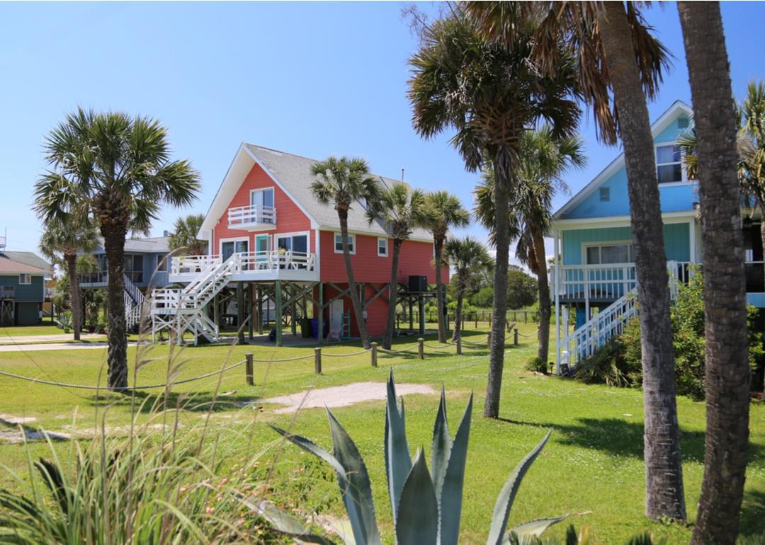 Pastel-colored, raised homes with palm trees.