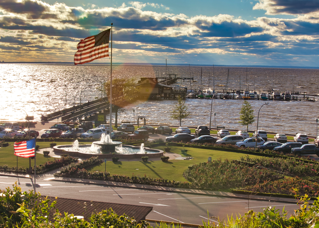 An American flag stands above a fountain on the edge of the ocean.