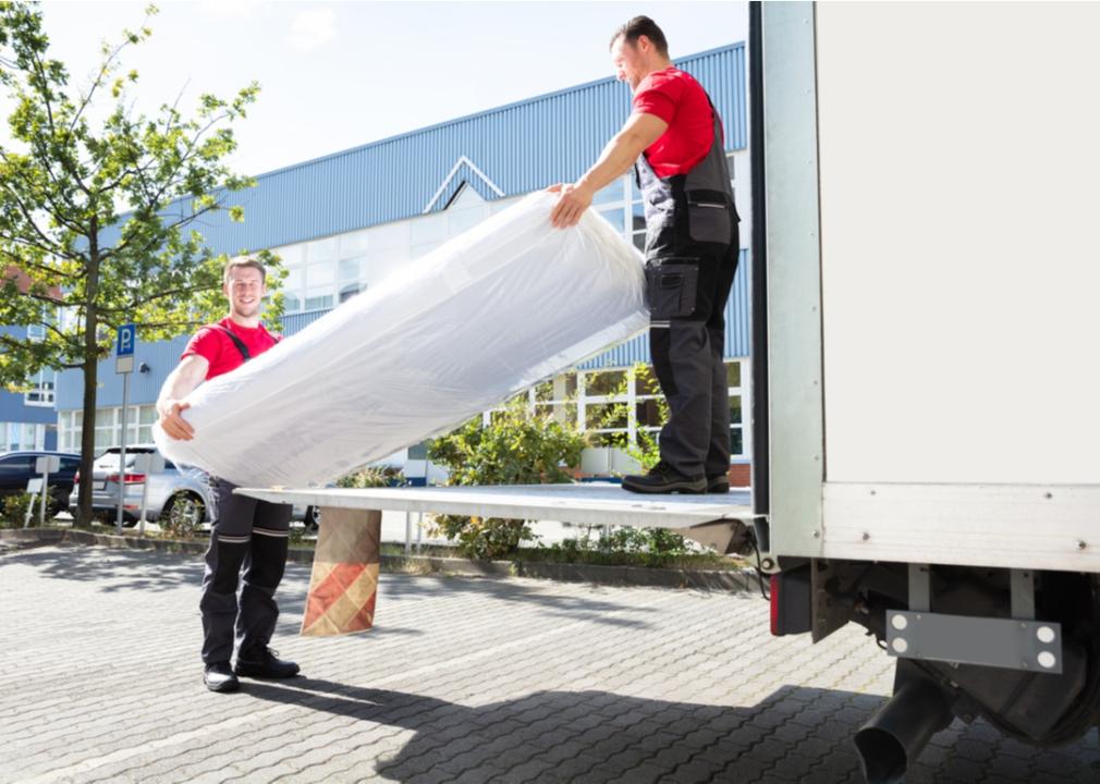 Movers carrying a mattress from a truck.