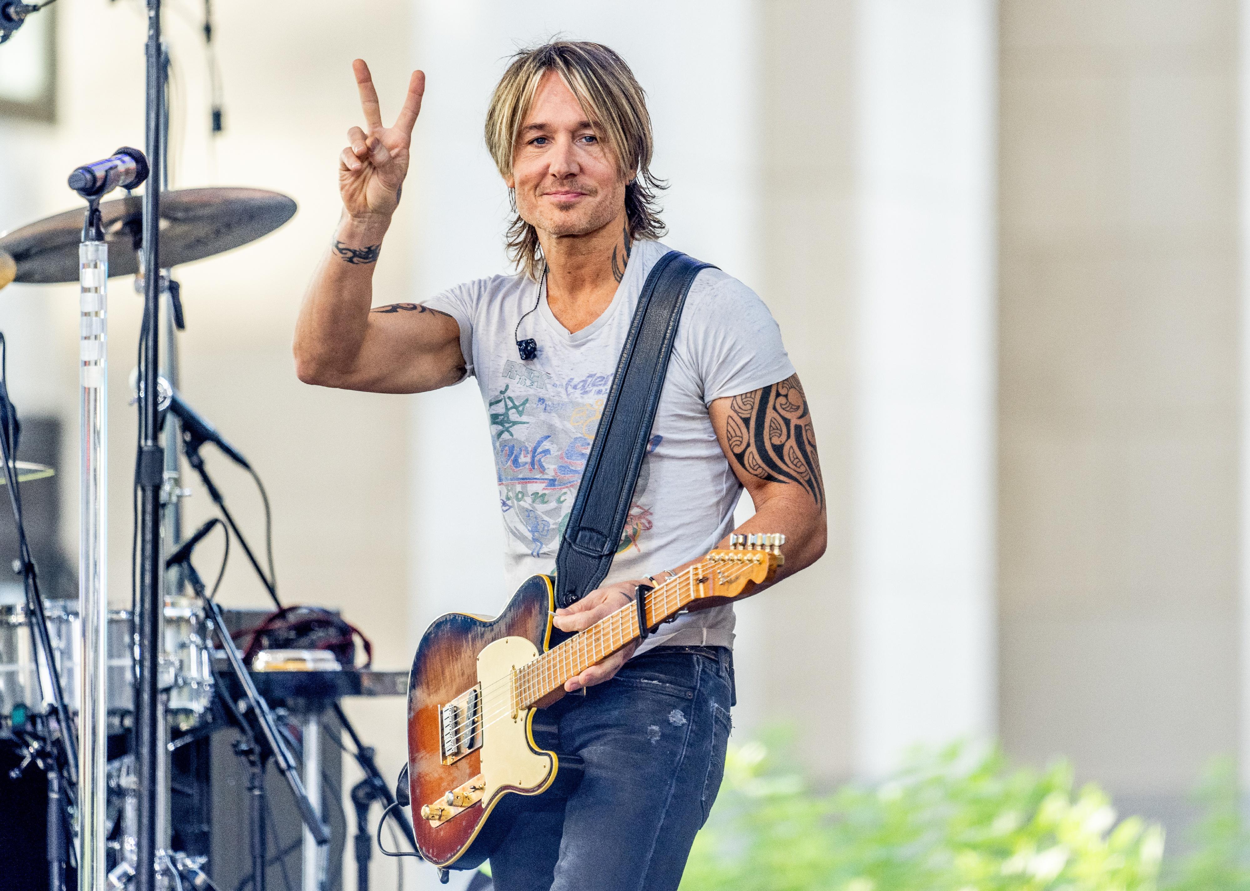 Keith Urban giving a peace sign onstage.