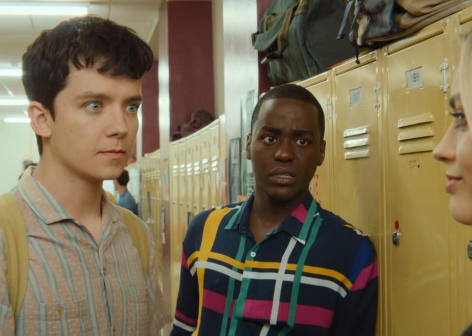 Three teens stand at their lockers talking.