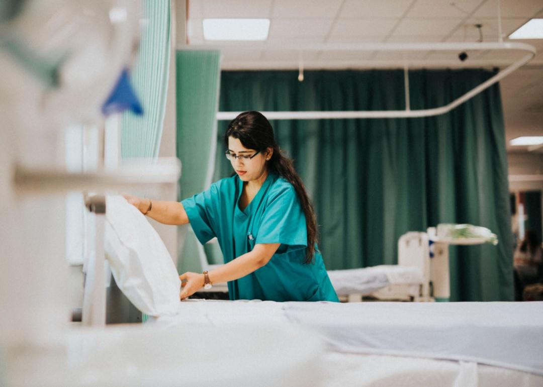 A nurse making a hospital bed.
