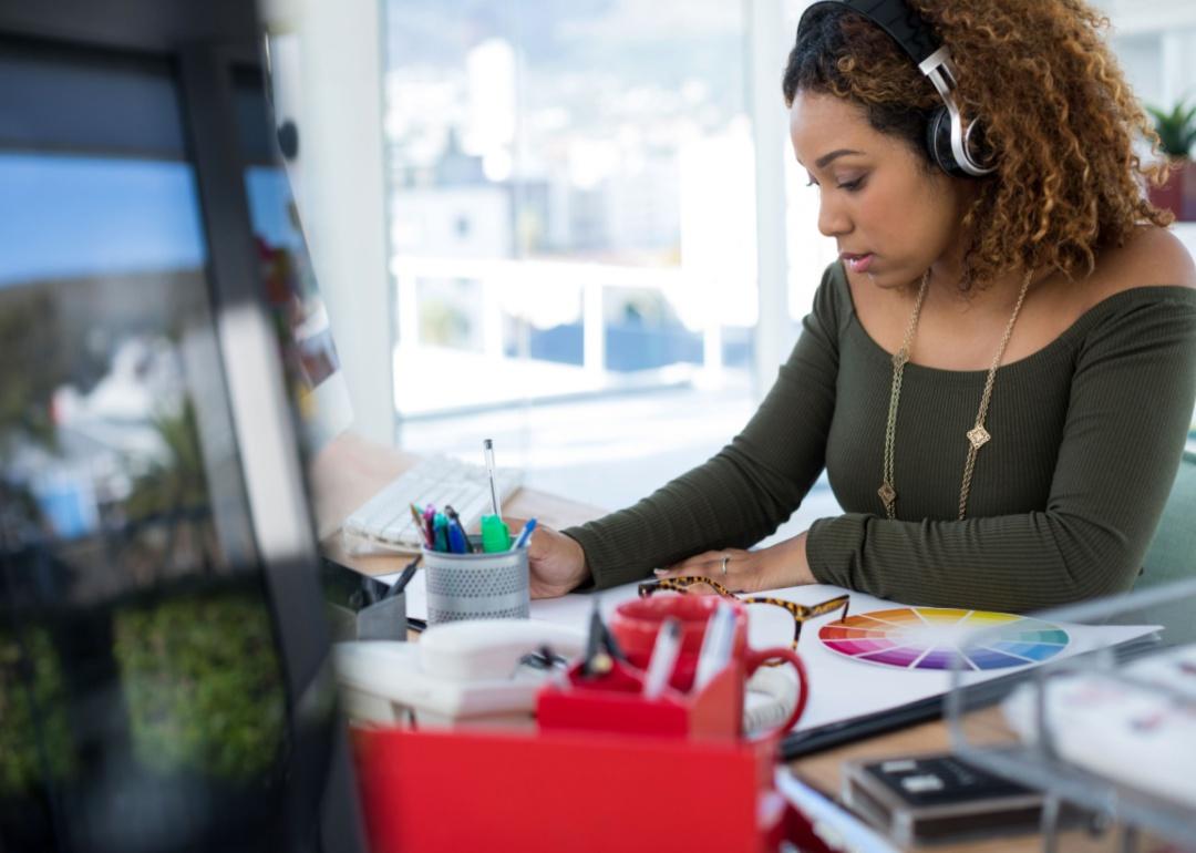 A woman listening to headphones while working at her desk.