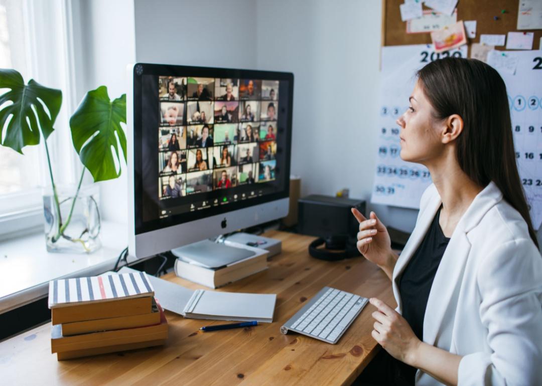 A woman sitting at a desk on a group Zoom call.