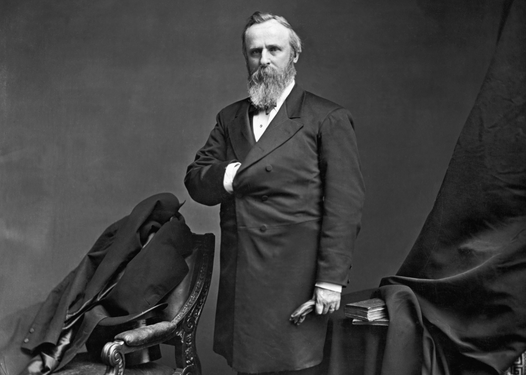 Rutherford B. Hayes posing for a portrait in a long dark suit jacket.