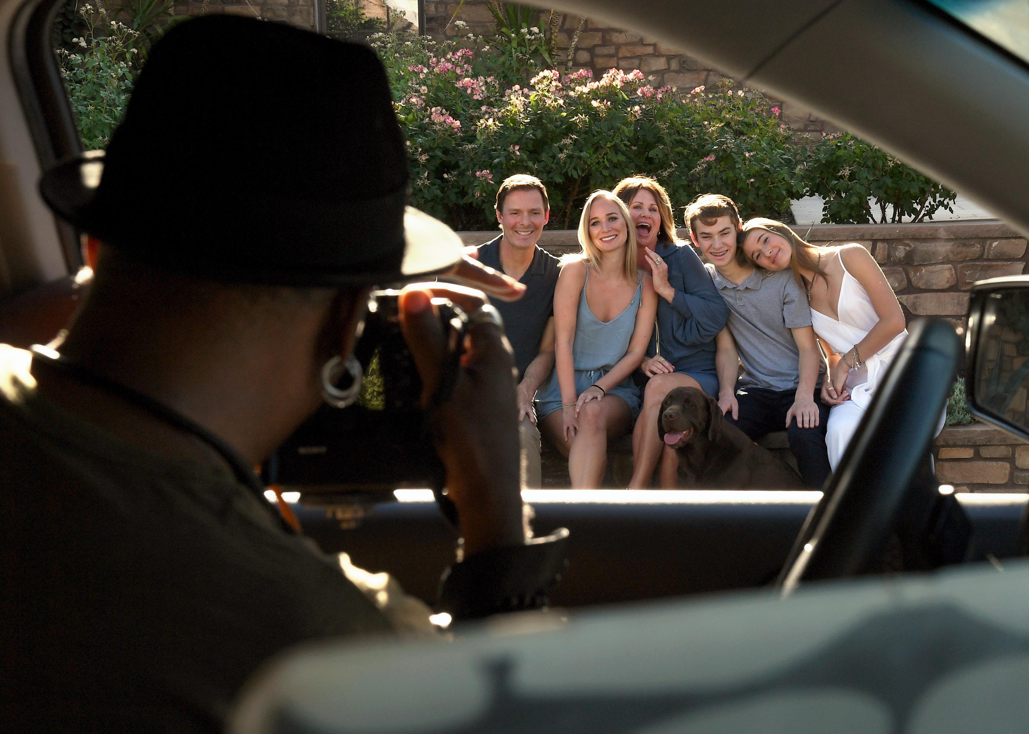 A photographer snaps a photo of a family from their car.