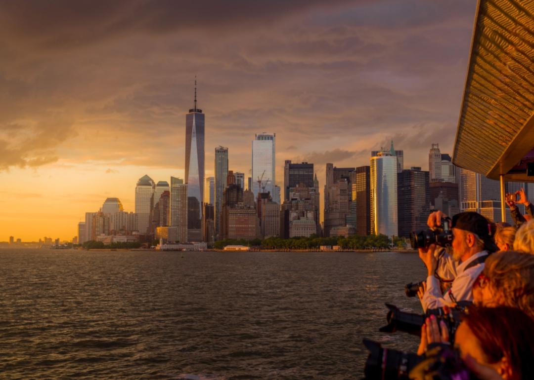 Photographers taking images of Manhattan at sunset from the water.