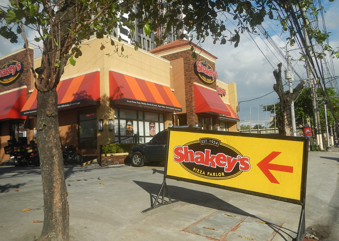 A Shakey's Pizza and parking lot with a yellow sign.