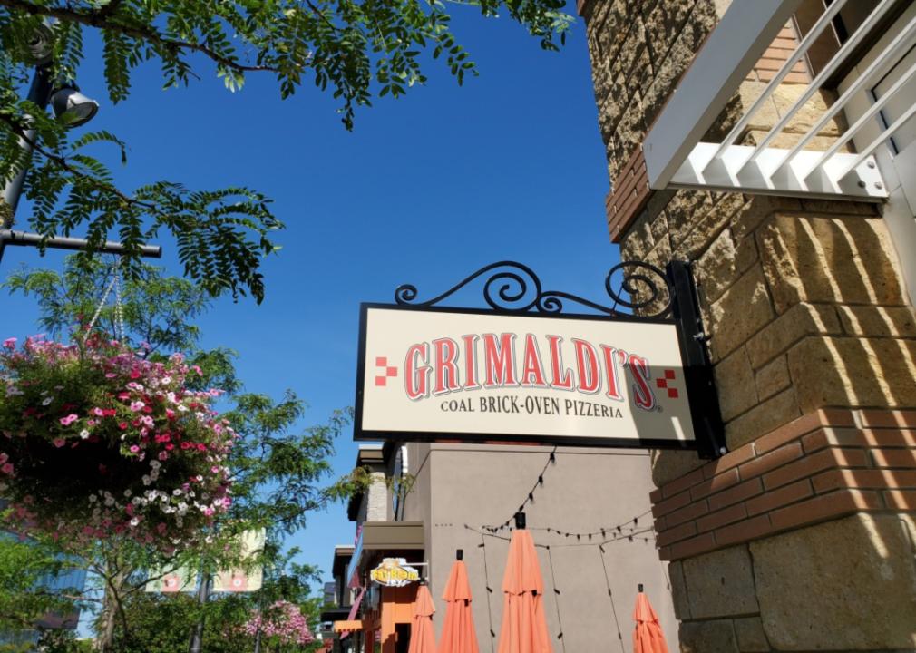 A Grimaldi's sign on a brick building surrounded by flowers.