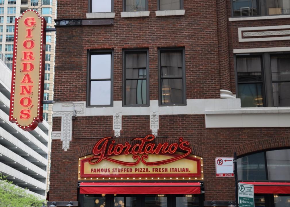 An ornate brick historic building with a red lit up Giordano's sign.