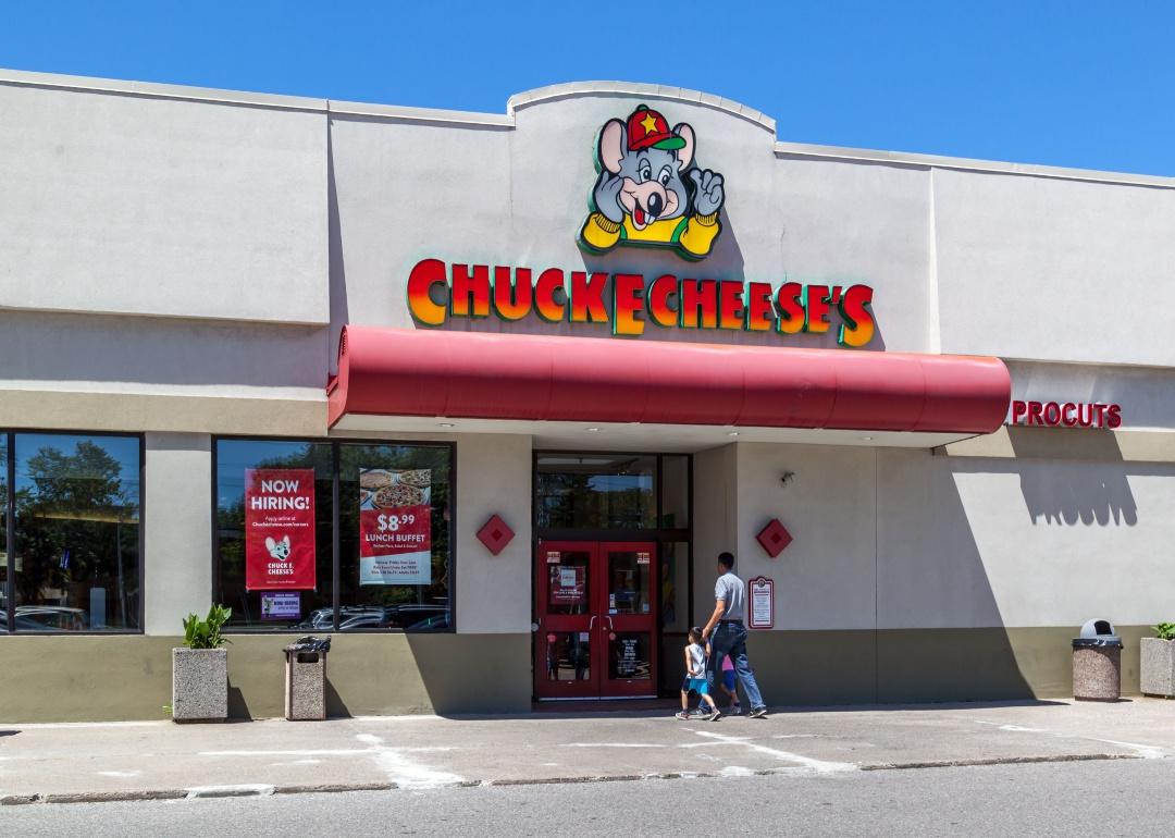 A man and two kids walking into a Chuck E. Cheese restaurant.