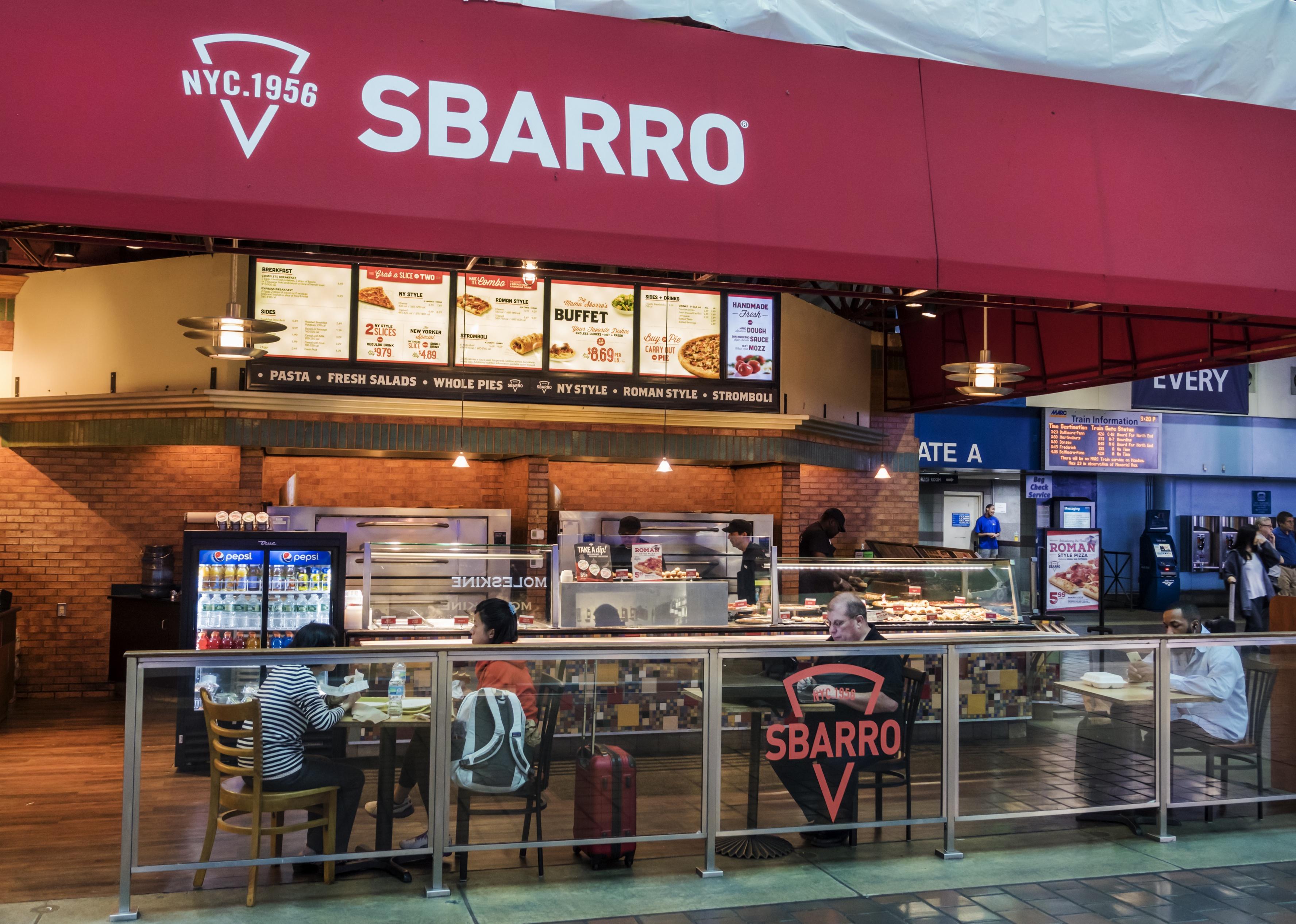 People sitting and eating at an Sbarro restaurant in union station.
