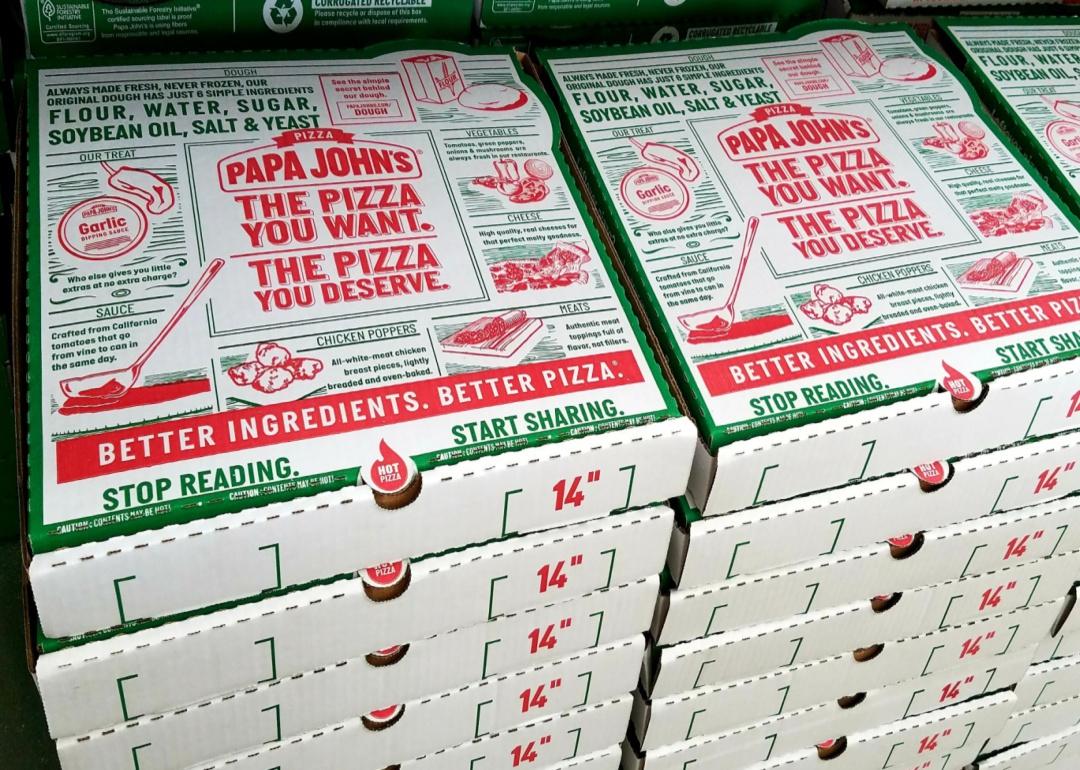 Stacks of Papa John's pizza boxes with green and red writing.