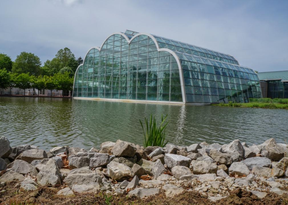 A large glass building surrounded by a lake.