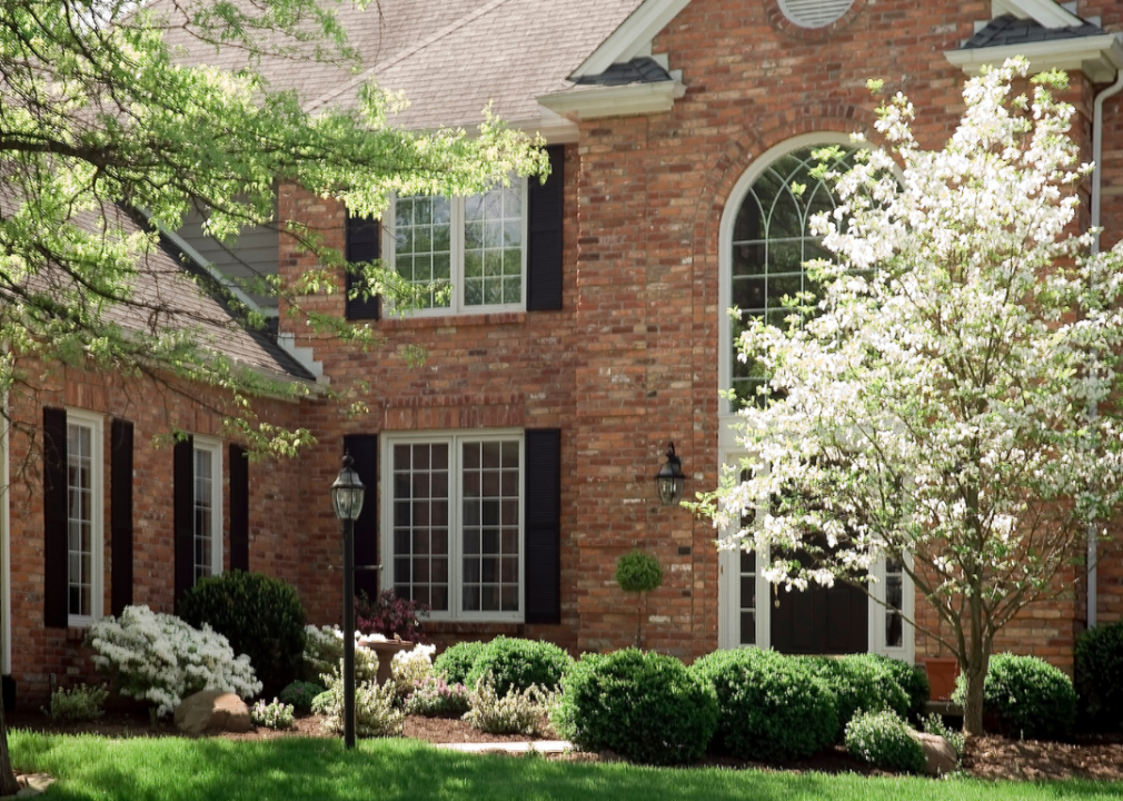 A two-story brick home with trees in bloom.