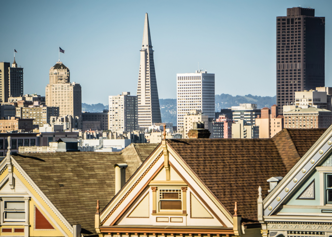 The tops of historic homes with the San Francisco skyline in the background.
