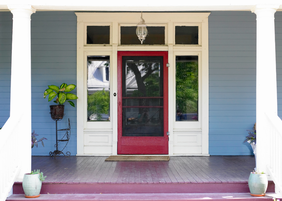 A historic front porch with a red door.