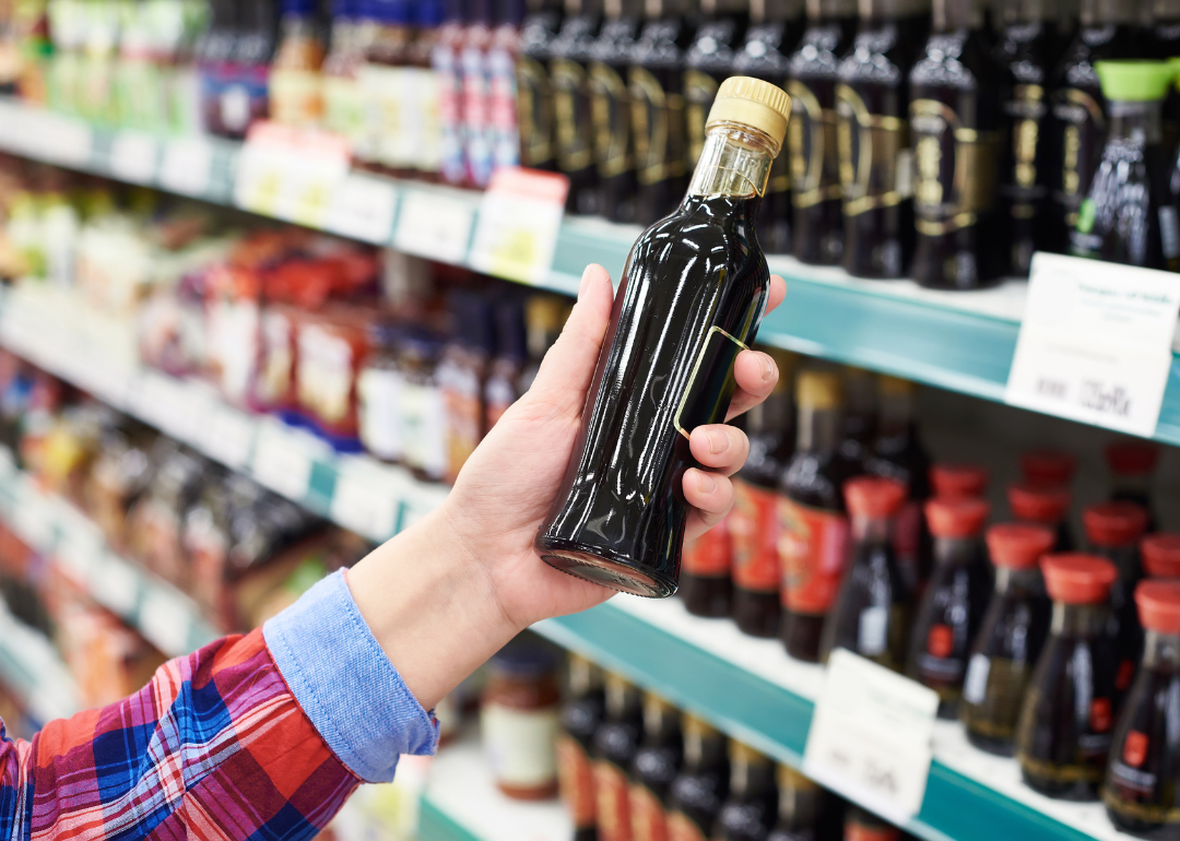 A person holding a bottle of soy sauce in the store.
