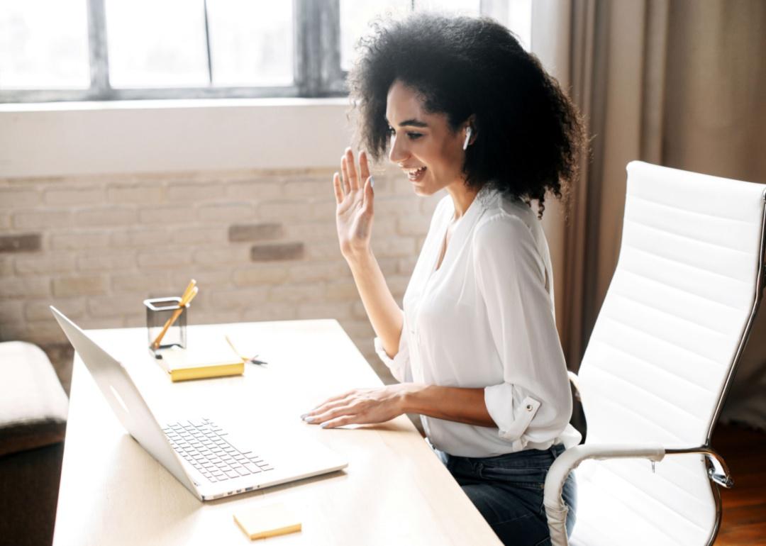 A woman waving hello during a remote meeting.