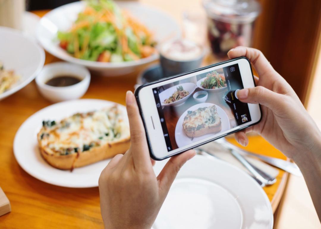 A person taking a photo of a meal on a phone.
