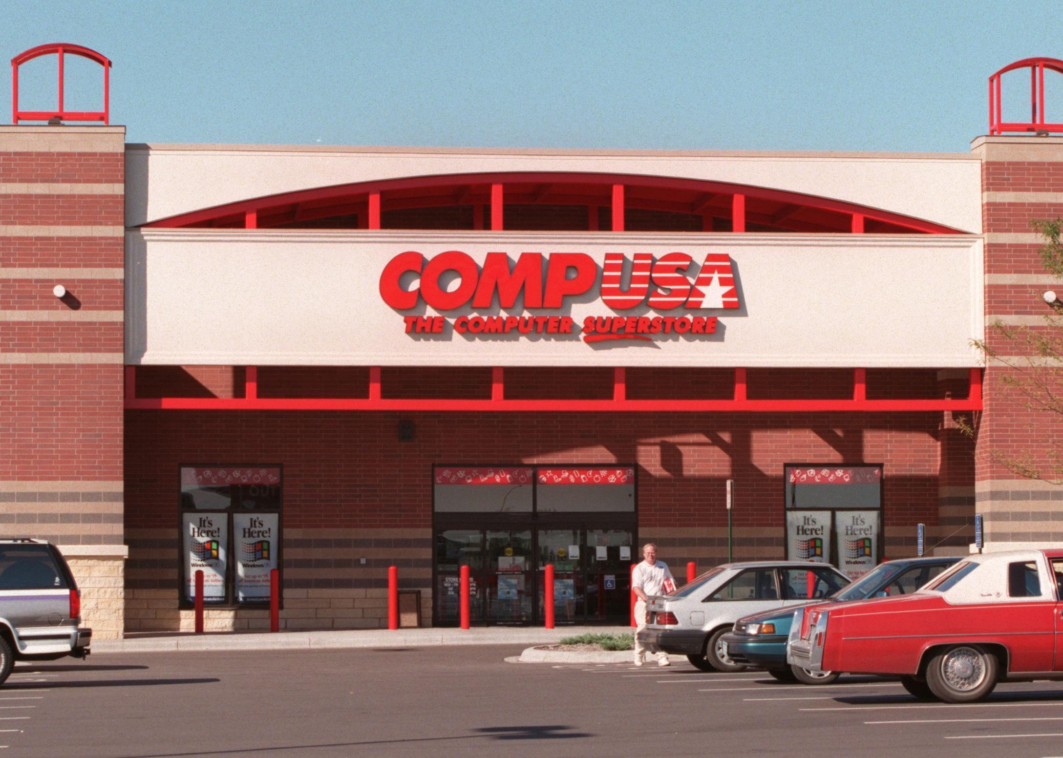 A man walking out of a CompUSA store.