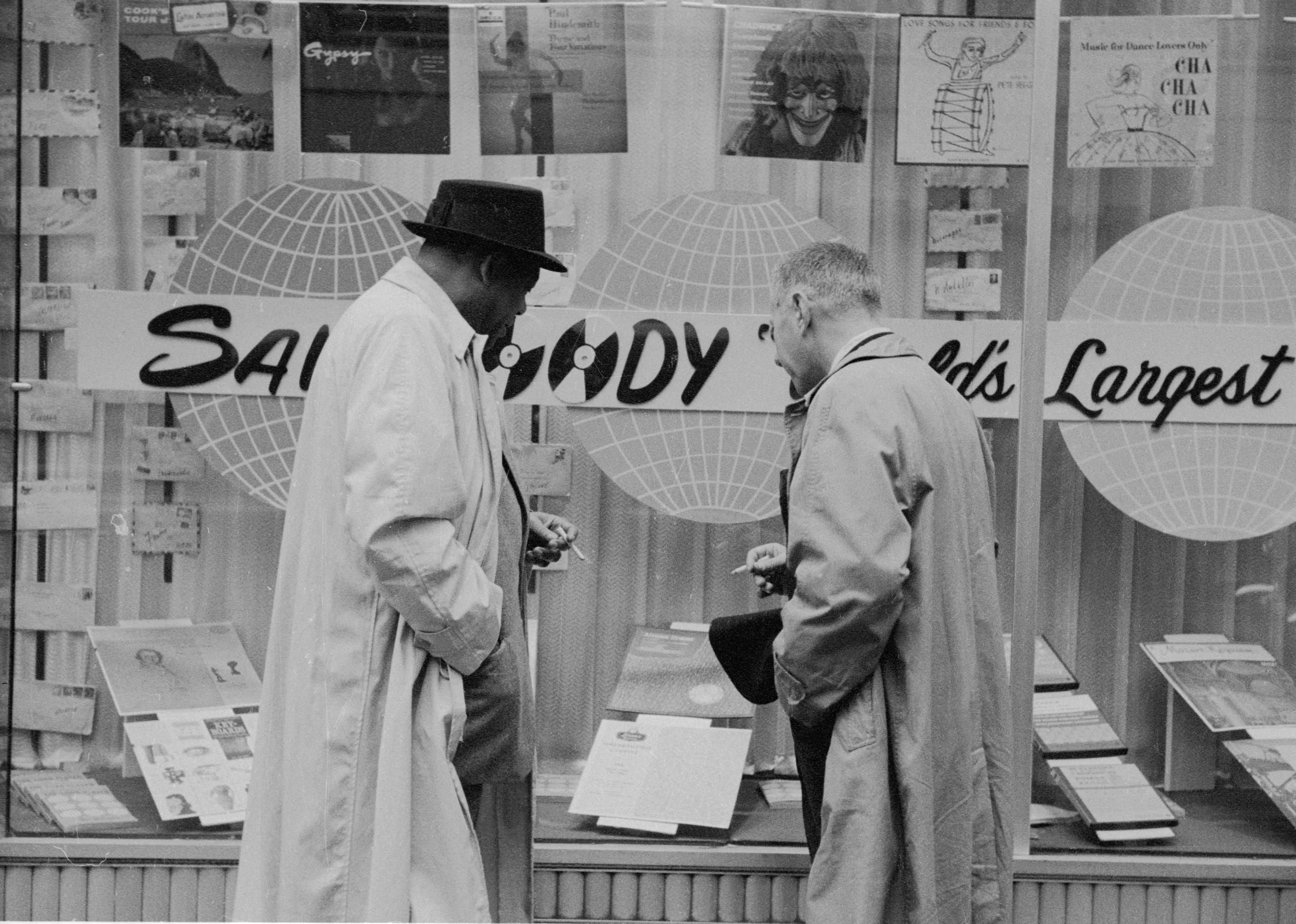 Two men looking into the glass windows of a Sam Goody store.