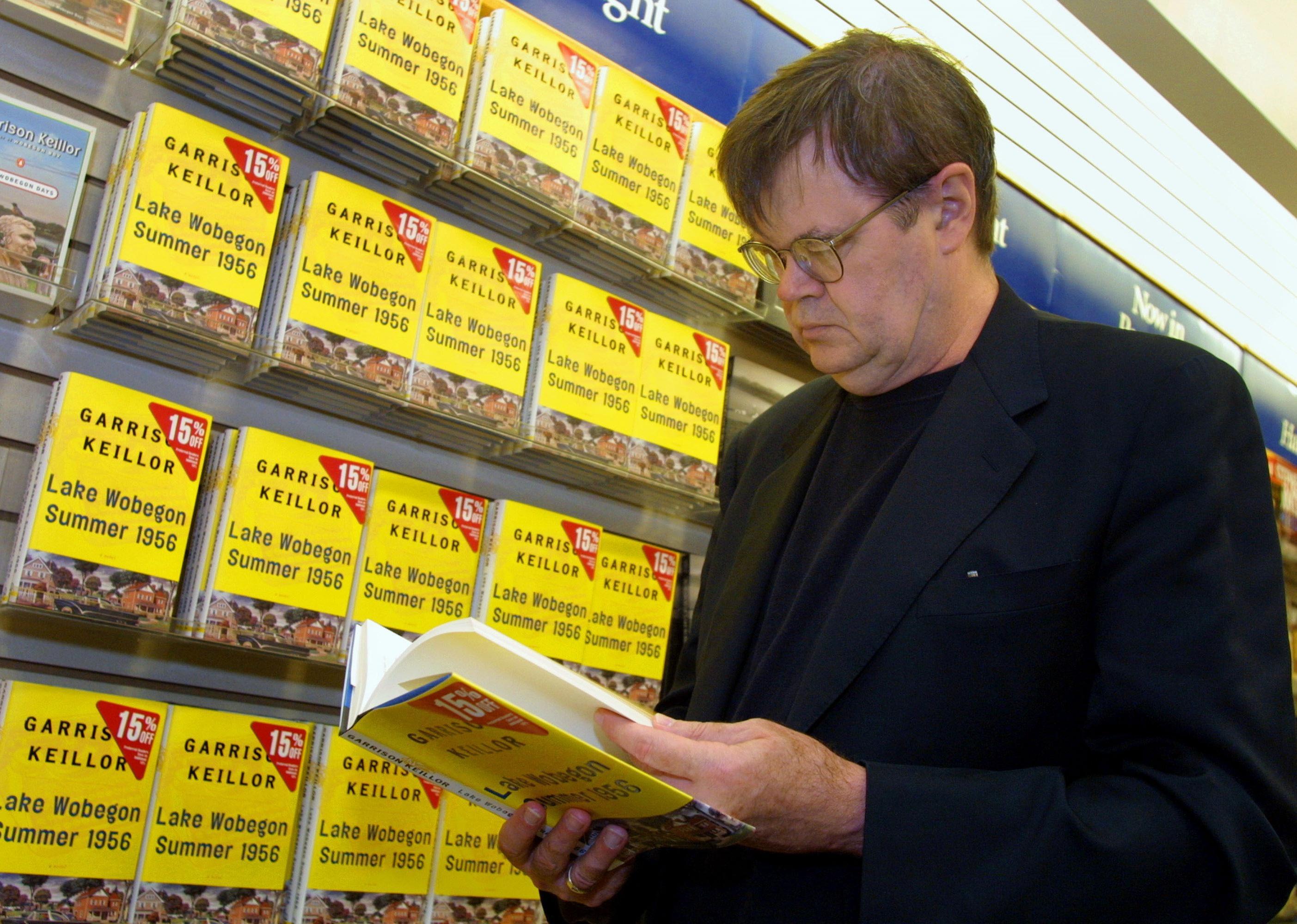 Garrison Keillor holding a copy of his book at Waldenbooks.
