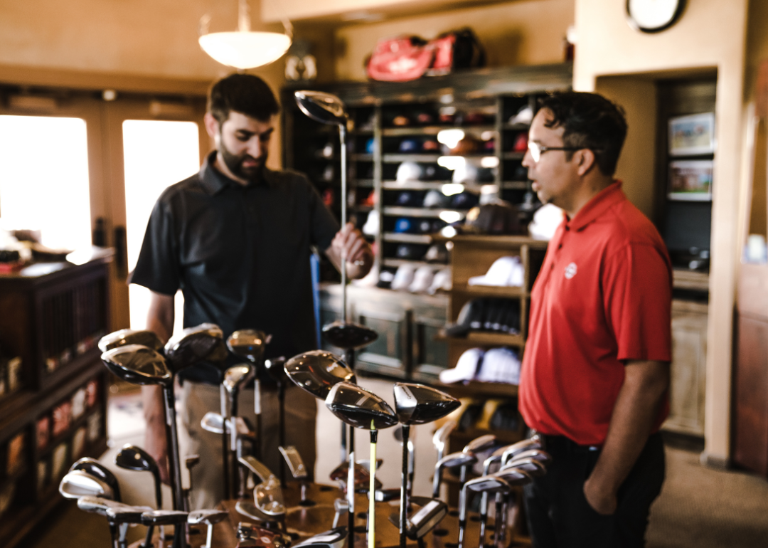 A person talking to a salesperson about golf clubs.