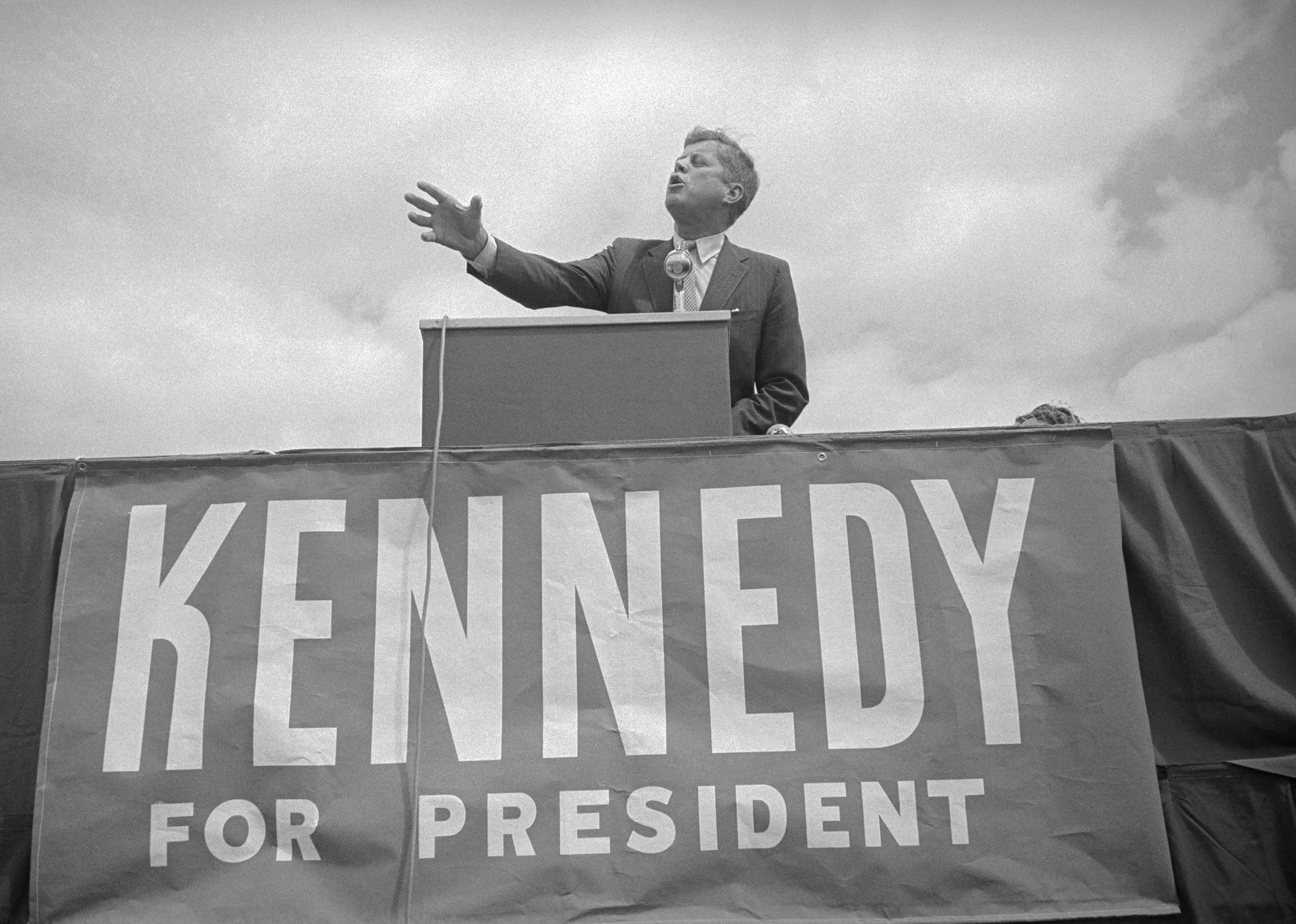 John F. Kennedy giving a campaign speech onstage.