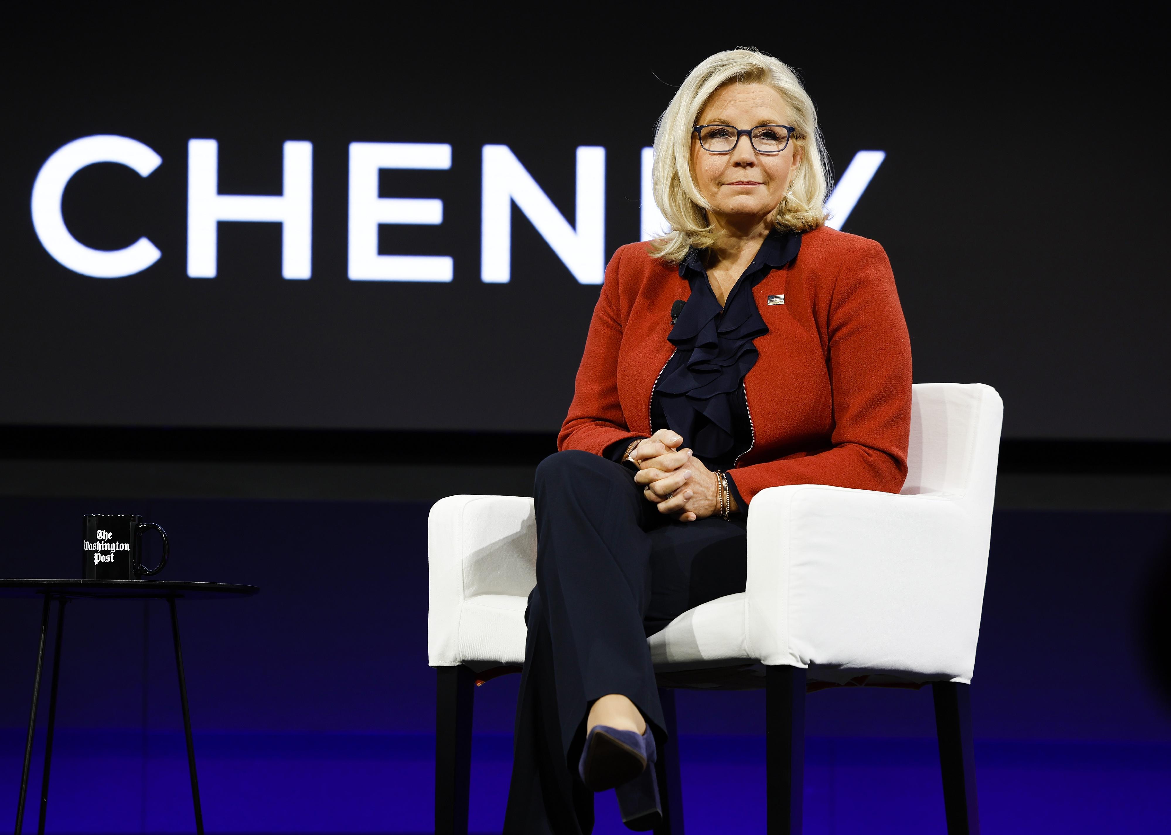 Liz Cheney on stage in black pants and a red sweater.