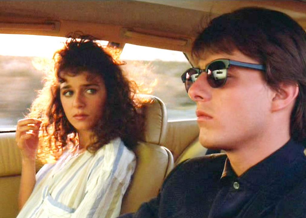Tom Cruise driving a car with Valeria Golino in the passenger seat.