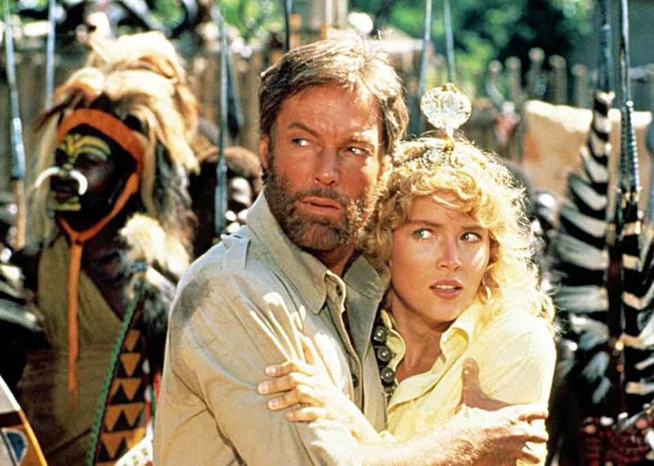 Sharon Stone and Richard Chamberlain holding onto each other scared of a tribe.