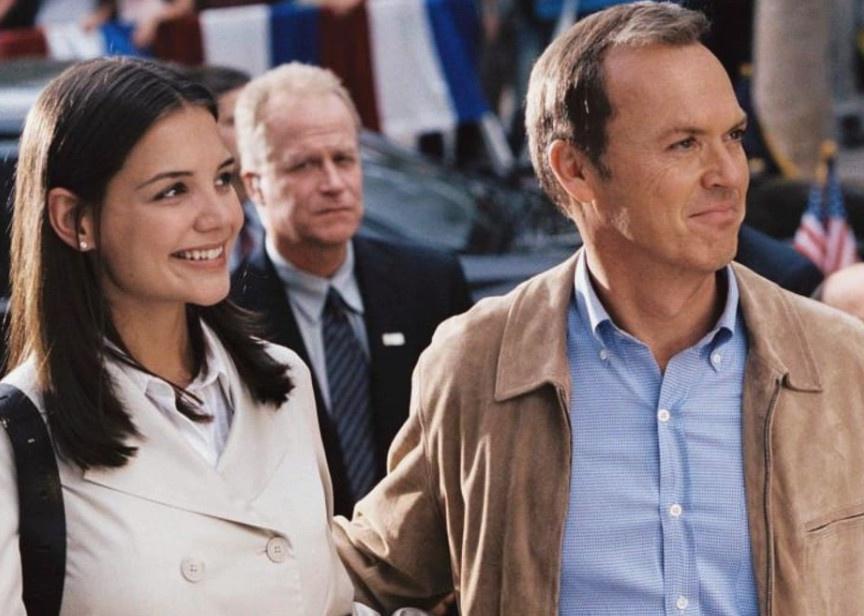 Katie Holmes and Michael Keaton standing together smiling.