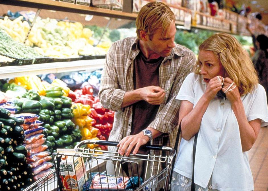 Elisabeth Shue and Aaron Eckhart pushing a grocery cart in the produce section of a store.