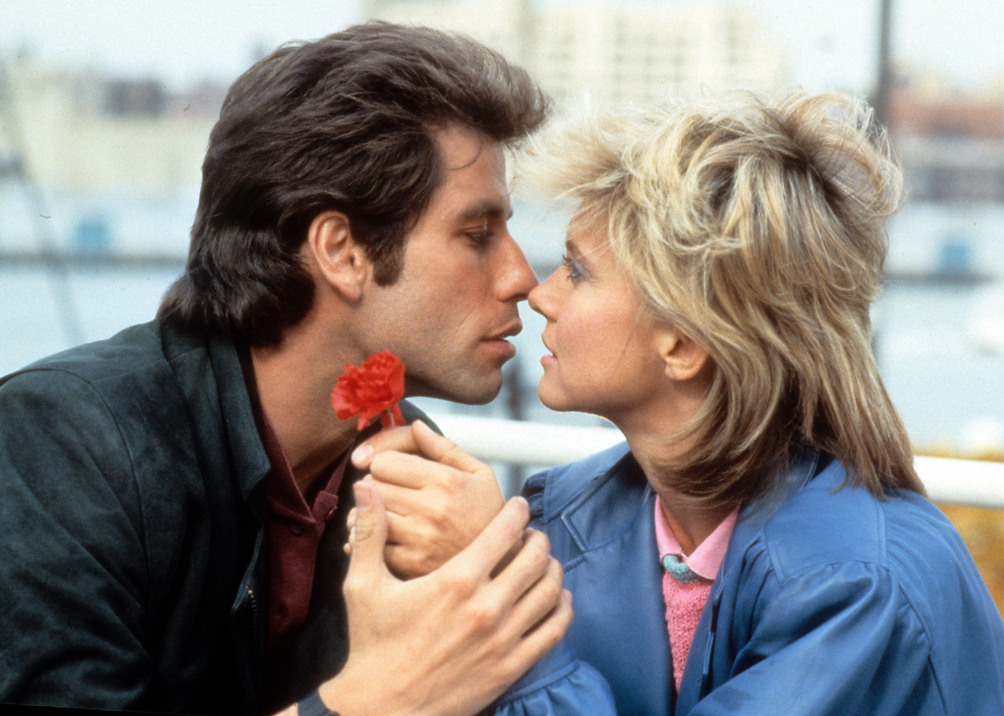 John Travolta and Olivia Newton-John looking longingly into each other's eyes as they go in for a kiss.