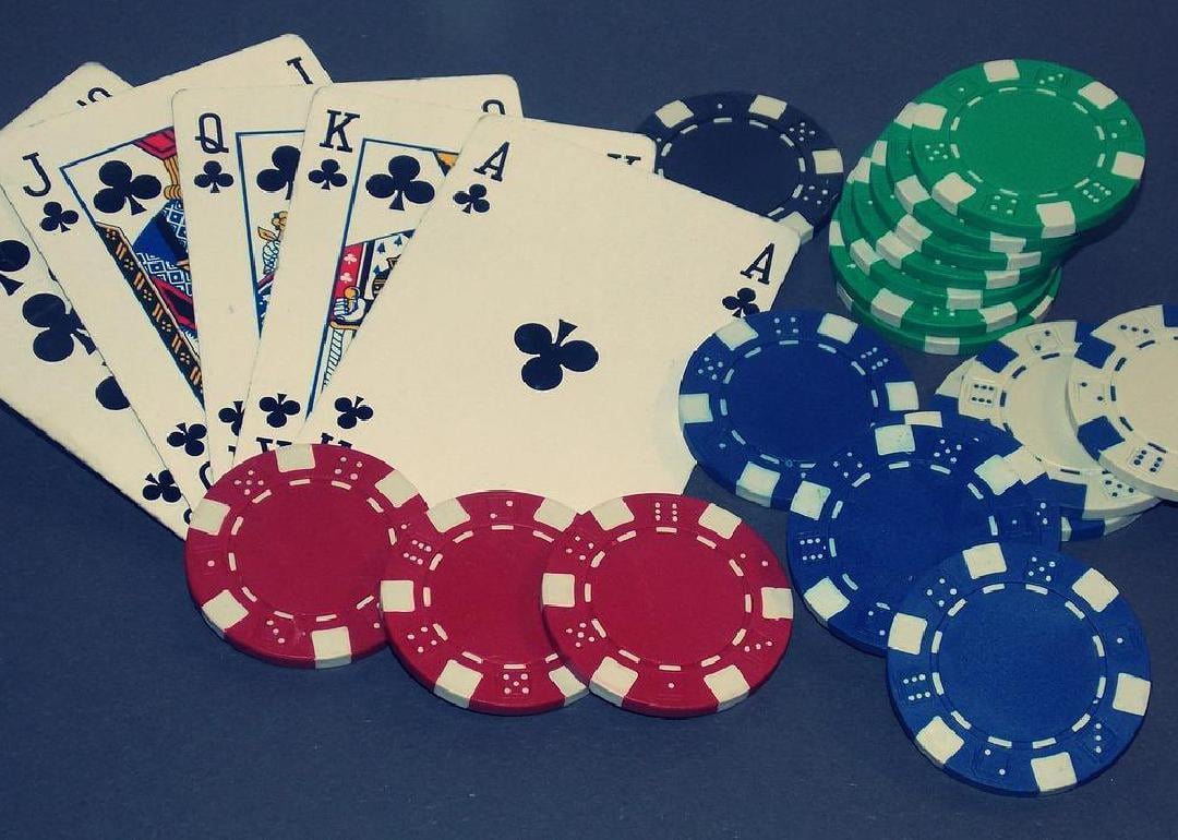 A royal flush on a table next to poker chips. 
