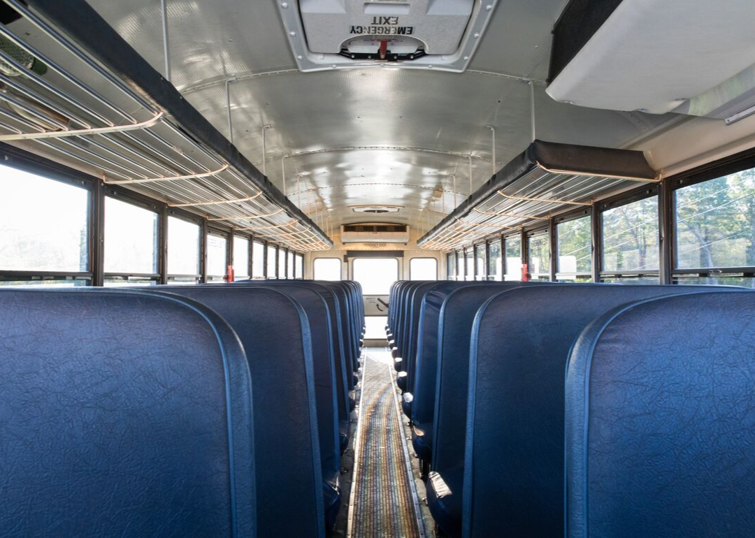 A school bus inside with empty blue seats.