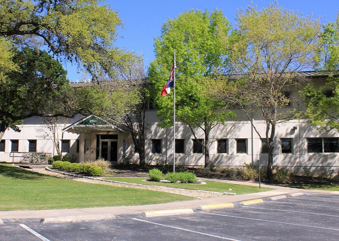 A stone school with a Texas and American flag in front.