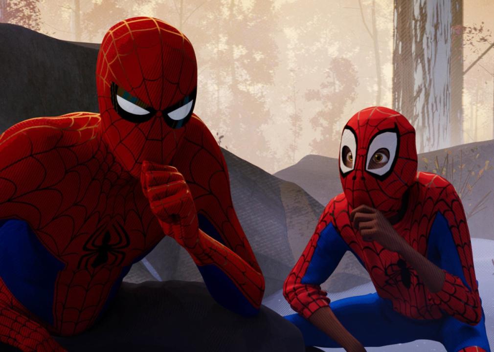 Spider man and a kid in a spider man suit both crouched down thinking.