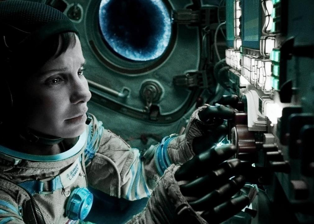 A woman astronaut stares at the controls inside a space capsule.