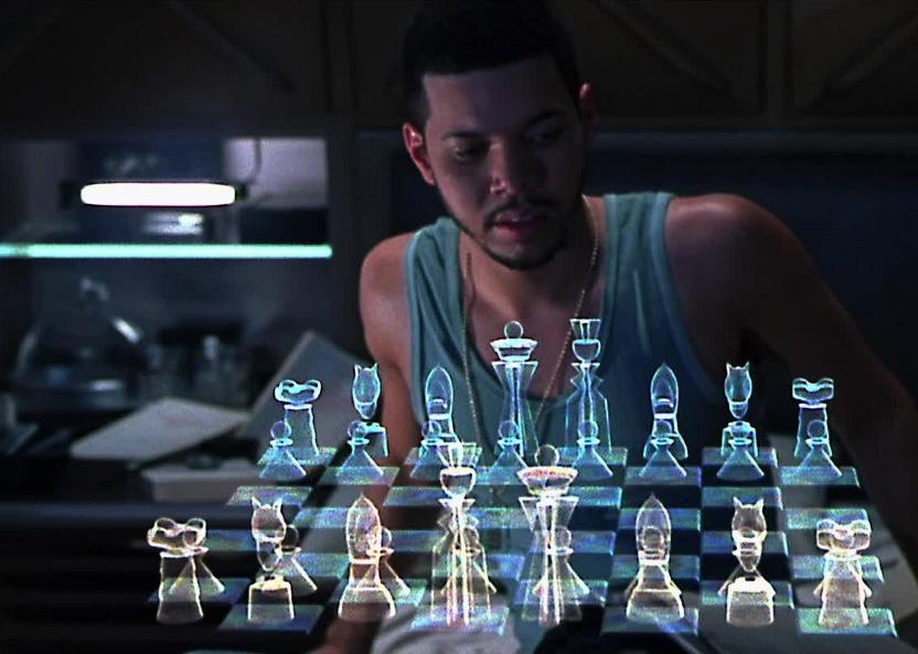 A man in a blue tank top sits in front of a holographic chess board.
