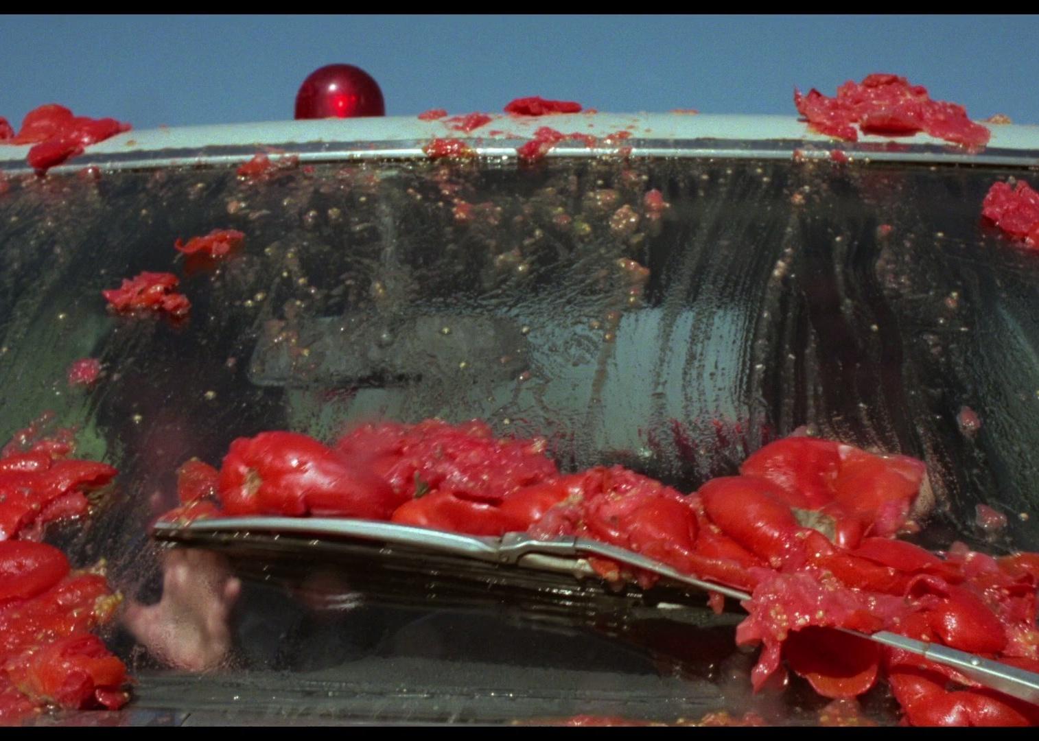 A car window covered in smashed tomatoes.