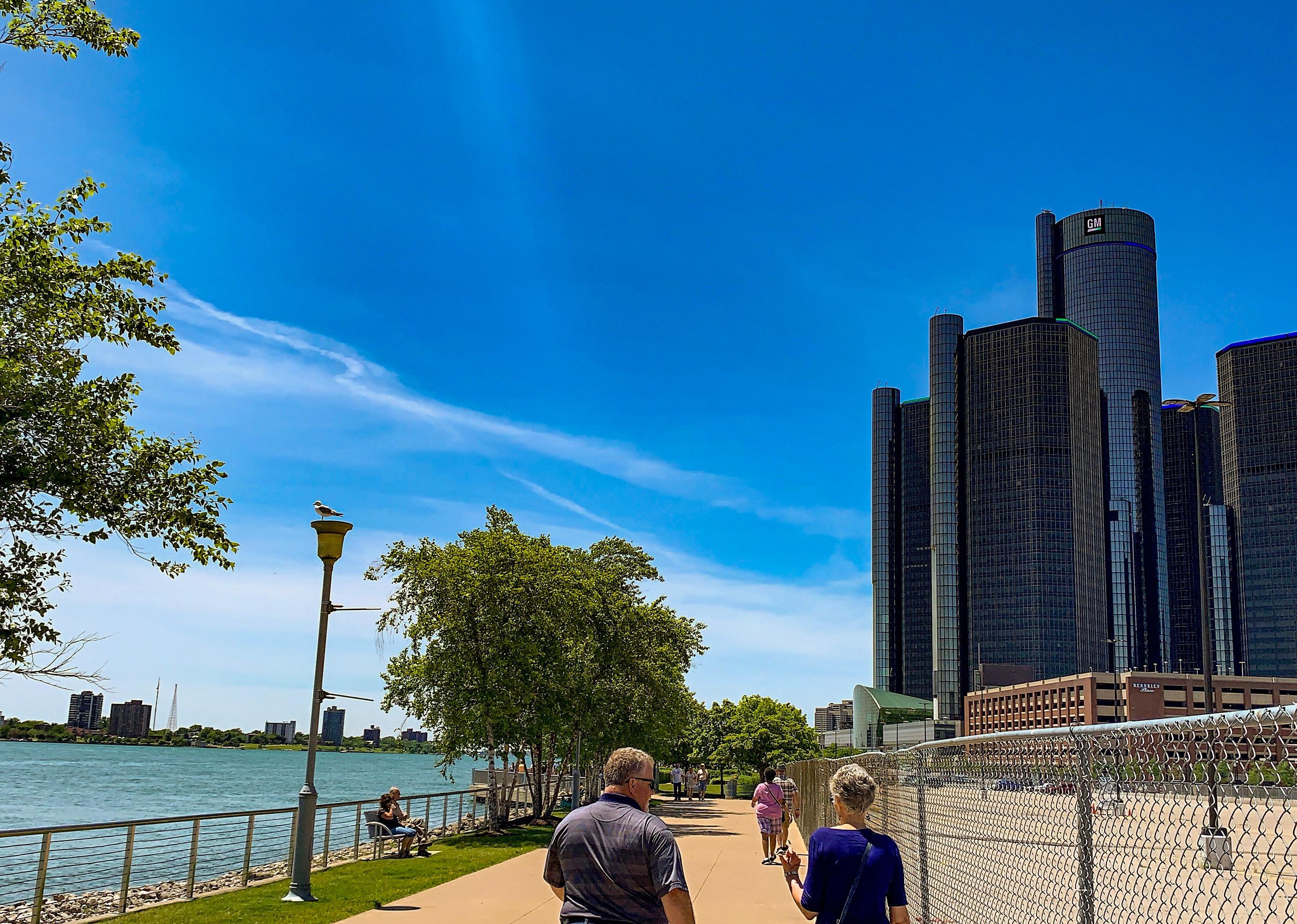 An older couple walking along the water near downtown Detroit.